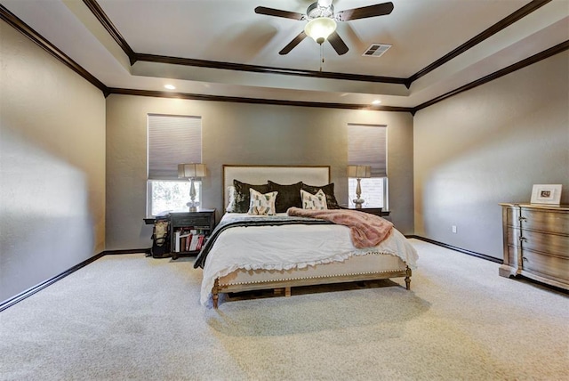 carpeted bedroom with baseboards, visible vents, a tray ceiling, and crown molding