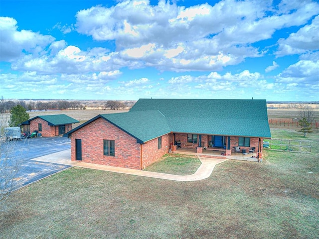 rustic home featuring a front yard, brick siding, fence, and roof with shingles