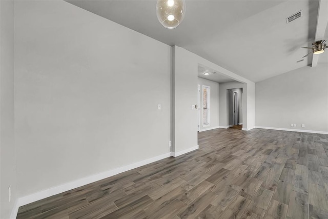 spare room with ceiling fan, visible vents, baseboards, vaulted ceiling, and dark wood-style floors