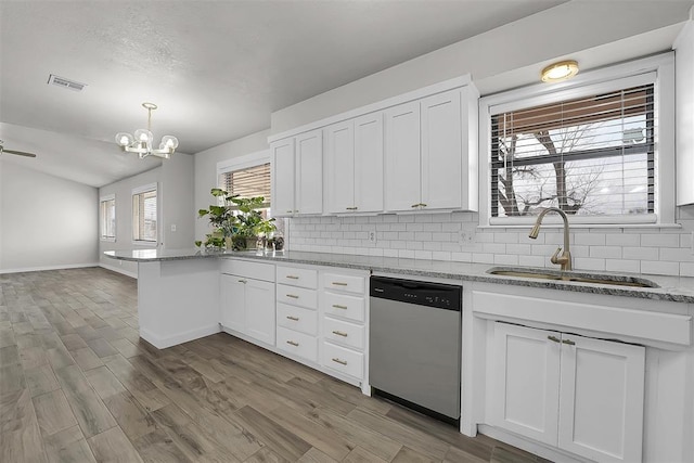 kitchen with visible vents, a peninsula, stainless steel dishwasher, white cabinetry, and a sink