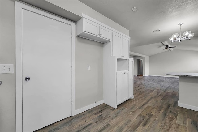 kitchen with baseboards, white cabinetry, vaulted ceiling, and dark wood-type flooring