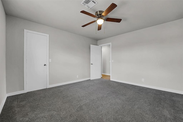 empty room with carpet floors, a ceiling fan, visible vents, and baseboards