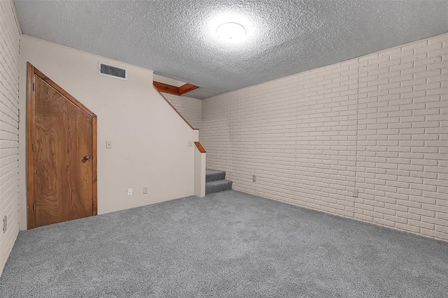 interior space with a textured ceiling, brick wall, visible vents, stairway, and carpet