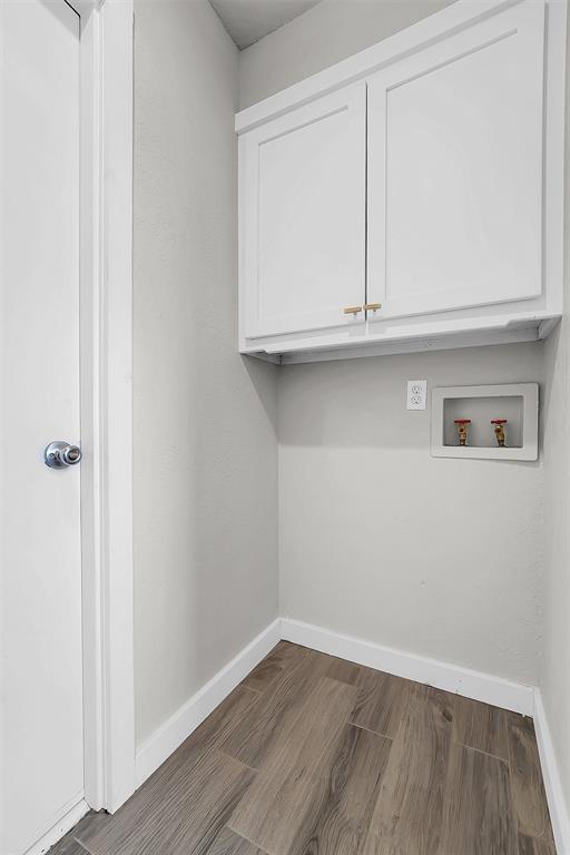 laundry room featuring washer hookup, wood finished floors, cabinet space, and baseboards