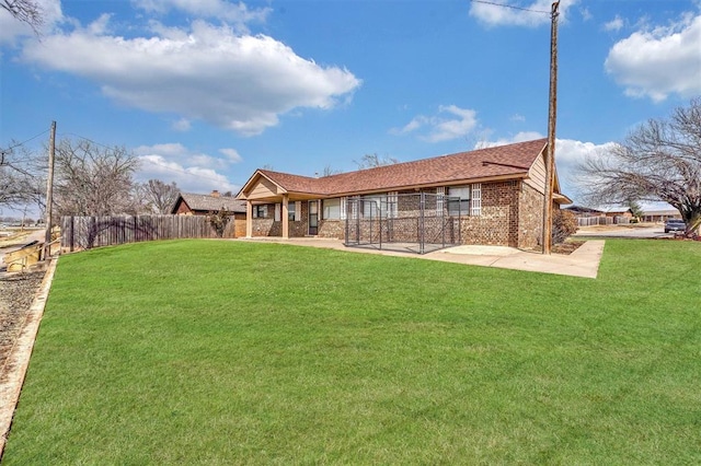 back of property with brick siding, a lawn, and fence