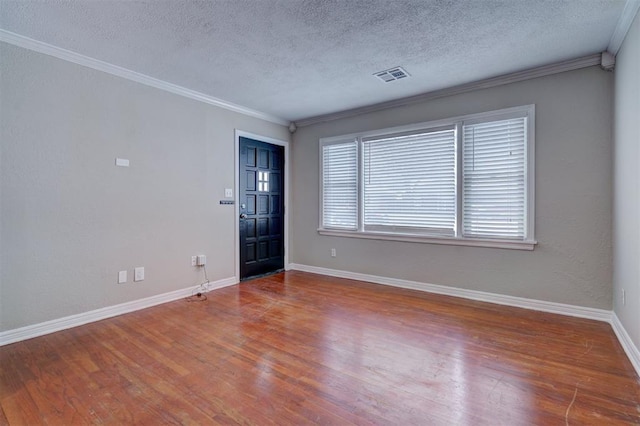 spare room featuring ornamental molding, wood finished floors, visible vents, and baseboards