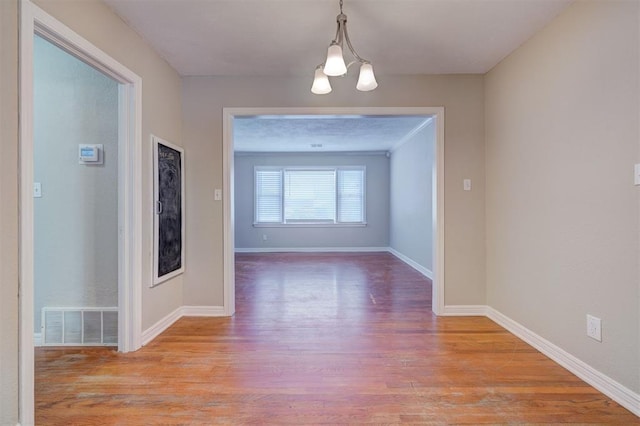 unfurnished dining area featuring light wood-type flooring, baseboards, and visible vents