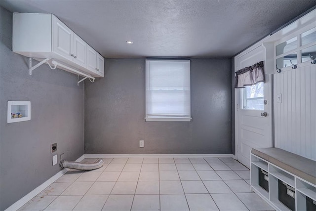 washroom with hookup for a washing machine, cabinet space, light tile patterned flooring, electric dryer hookup, and a textured ceiling