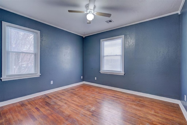 unfurnished room featuring baseboards, wood finished floors, visible vents, and crown molding