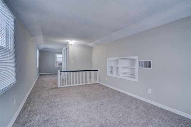 spare room with baseboards, visible vents, a textured ceiling, and carpet flooring