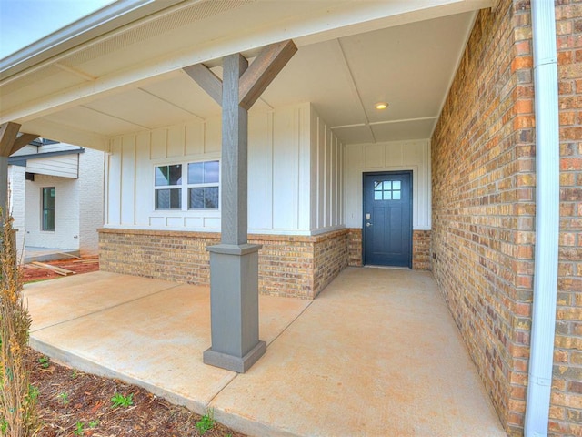 view of exterior entry with brick siding and board and batten siding