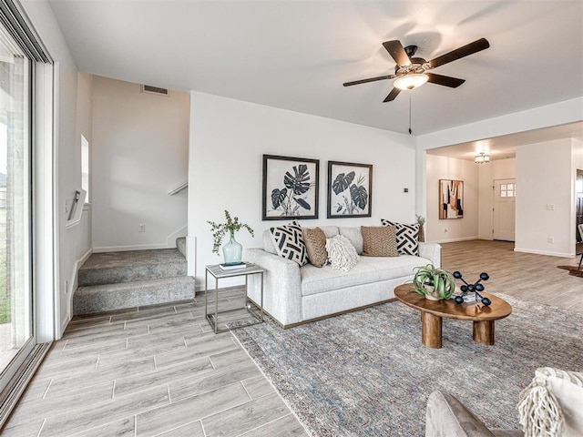 living room with visible vents, baseboards, ceiling fan, stairway, and wood tiled floor