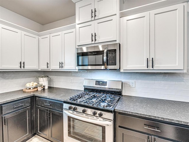 kitchen with dark countertops, appliances with stainless steel finishes, decorative backsplash, and white cabinets