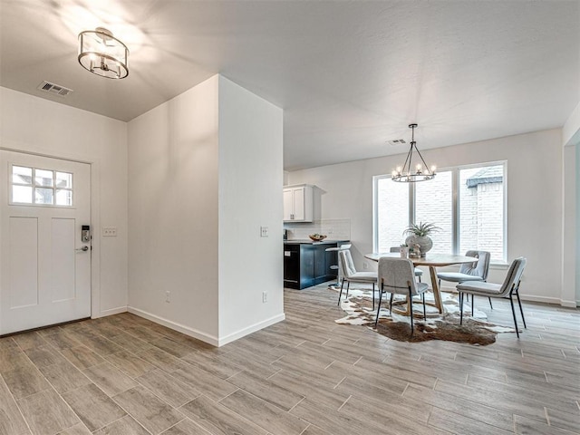 dining room with wood tiled floor, visible vents, baseboards, and an inviting chandelier