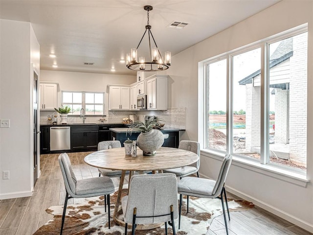 dining area with baseboards, visible vents, a notable chandelier, and wood finish floors