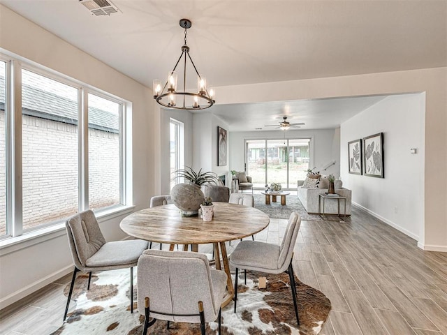 dining room featuring ceiling fan with notable chandelier, light wood-style flooring, visible vents, and baseboards