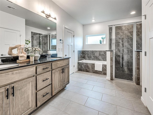 bathroom with visible vents, a sink, a shower stall, and a garden tub