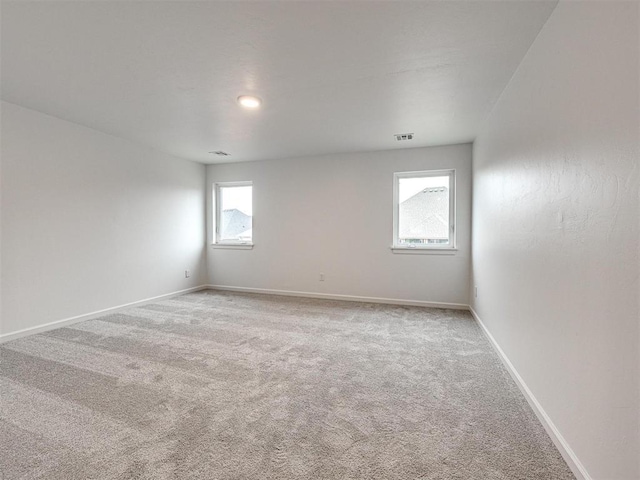 carpeted spare room with visible vents and baseboards