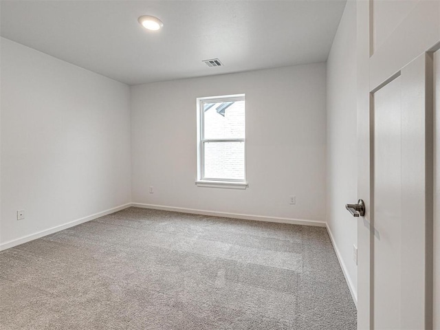 carpeted spare room with visible vents and baseboards