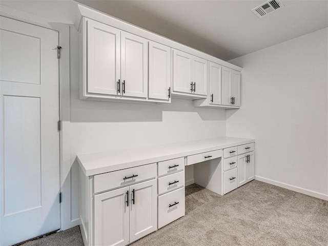 office with light carpet, built in study area, visible vents, and baseboards