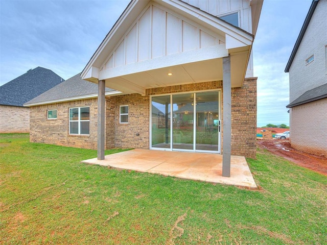 back of property with board and batten siding, brick siding, a patio, and a lawn