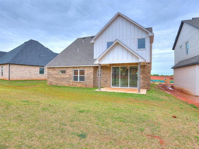 back of house with brick siding, a yard, a patio, a shingled roof, and board and batten siding