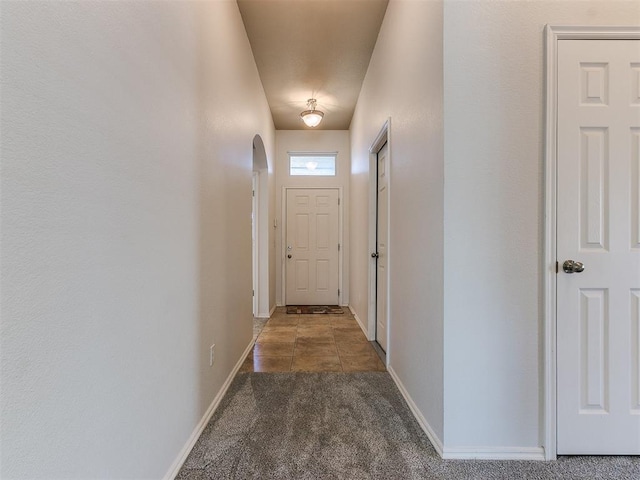 hall with arched walkways, carpet flooring, and baseboards