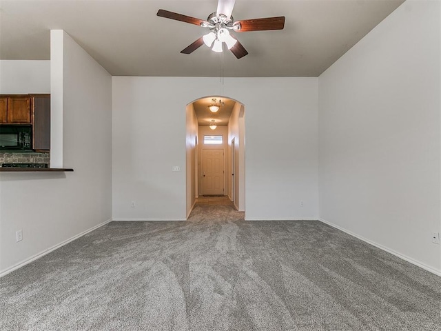 unfurnished room featuring arched walkways, carpet flooring, a ceiling fan, and baseboards