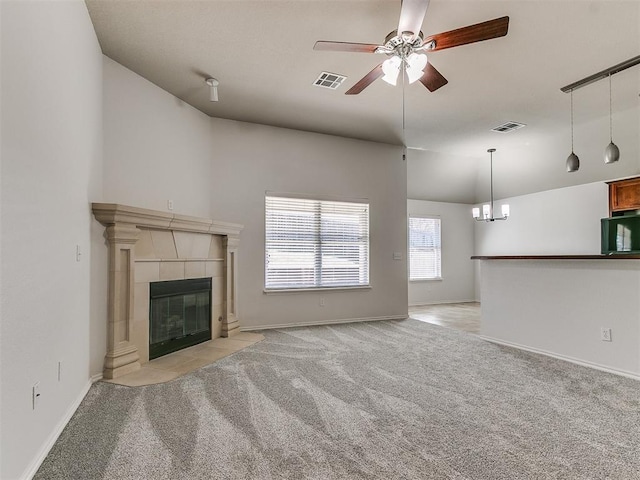 unfurnished living room with light colored carpet, visible vents, a fireplace, and ceiling fan with notable chandelier