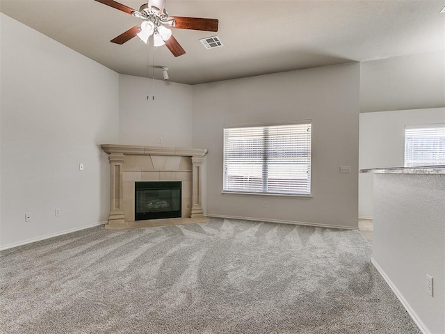 unfurnished living room with ceiling fan, a tiled fireplace, carpet flooring, and visible vents