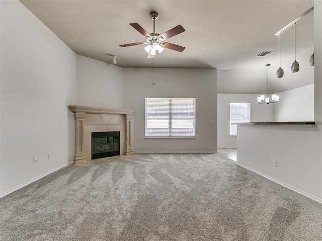 unfurnished living room featuring a fireplace, visible vents, carpet flooring, baseboards, and ceiling fan with notable chandelier