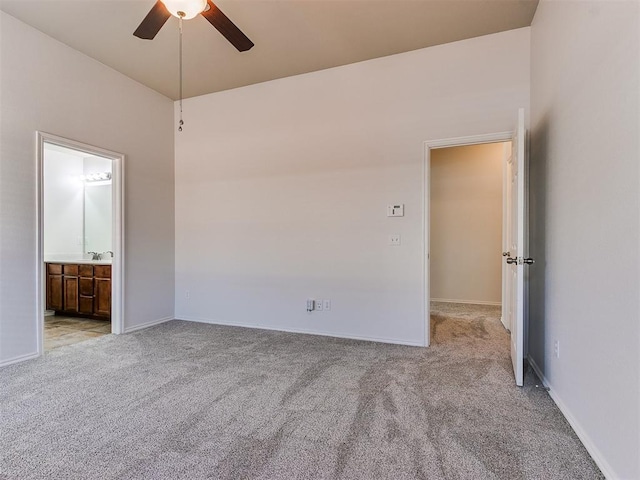 unfurnished bedroom featuring connected bathroom, light colored carpet, a sink, and baseboards