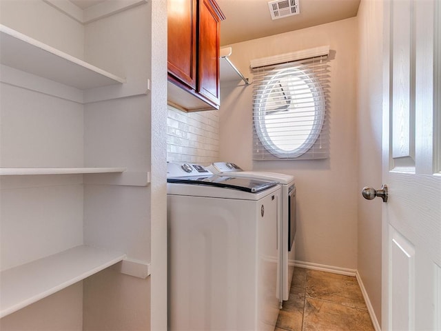 laundry room with visible vents, cabinet space, washing machine and dryer, stone finish flooring, and baseboards