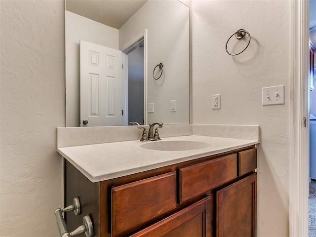 bathroom featuring a textured wall and vanity