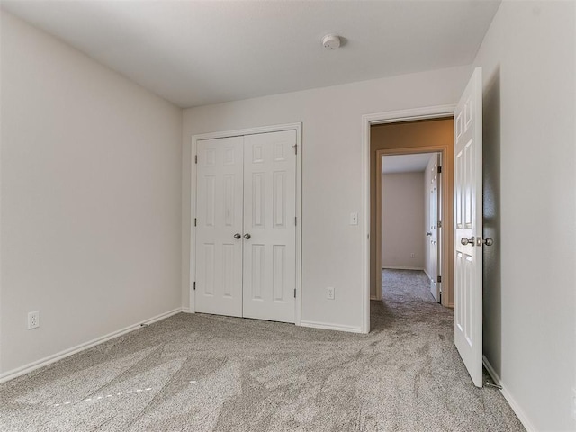 unfurnished bedroom with baseboards, a closet, and light colored carpet