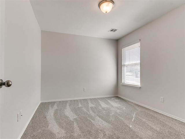 spare room with carpet, visible vents, and baseboards