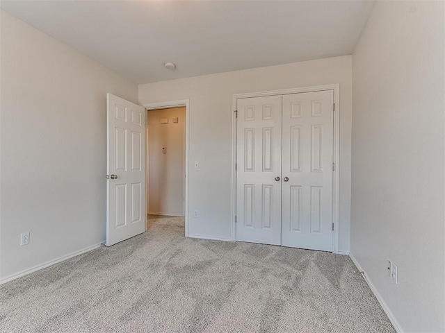 unfurnished bedroom with carpet, a closet, and baseboards