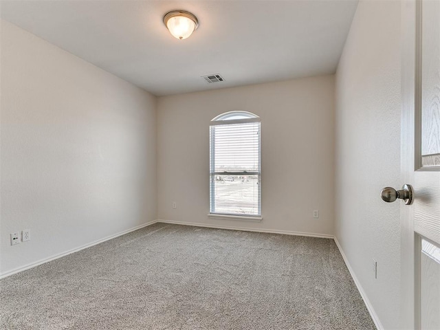 empty room featuring carpet floors, visible vents, and baseboards