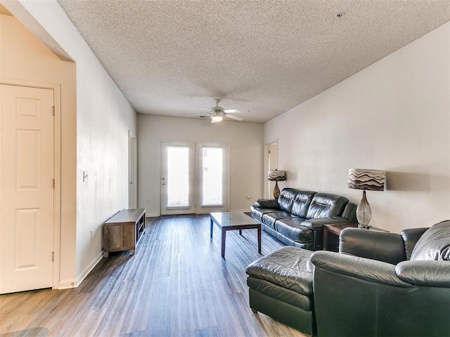 living area featuring ceiling fan, a textured ceiling, baseboards, and wood finished floors