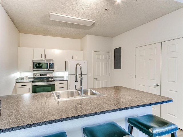 kitchen with stainless steel appliances, dark countertops, a sink, and a breakfast bar