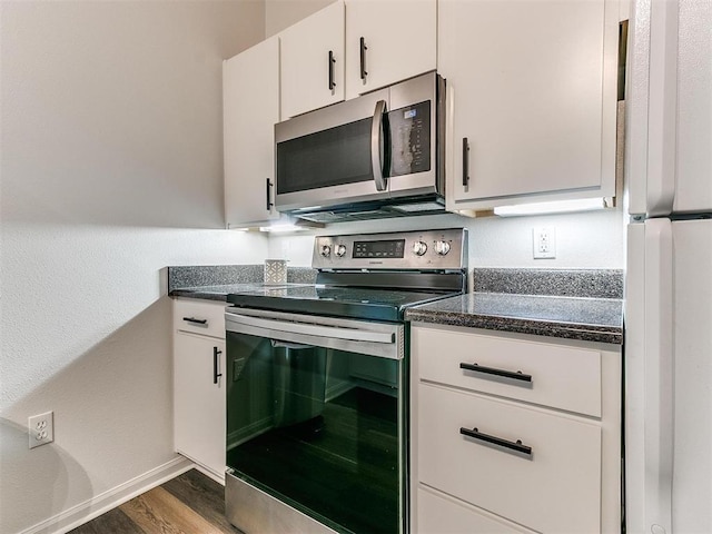 kitchen featuring baseboards, white cabinets, appliances with stainless steel finishes, dark stone countertops, and dark wood-style flooring