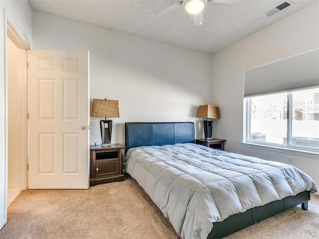 carpeted bedroom with a ceiling fan, visible vents, and a textured ceiling