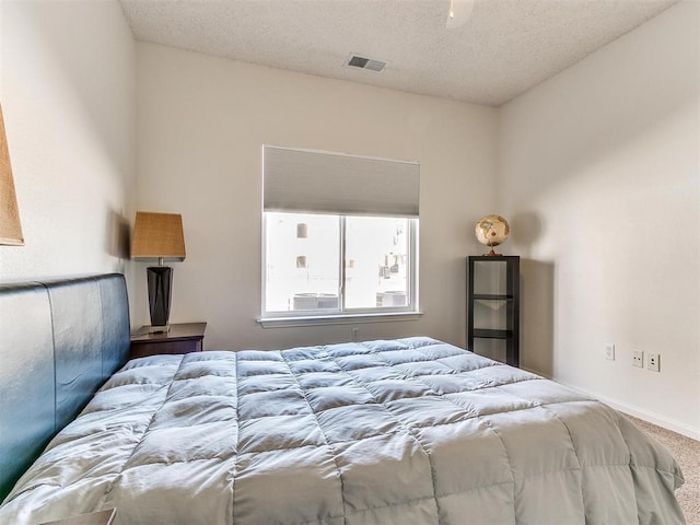 bedroom with carpet floors, visible vents, a textured ceiling, and baseboards