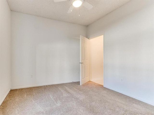 empty room with a textured ceiling, ceiling fan, carpet flooring, and baseboards