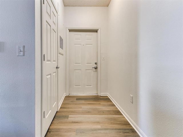 doorway to outside featuring light wood-style flooring and baseboards