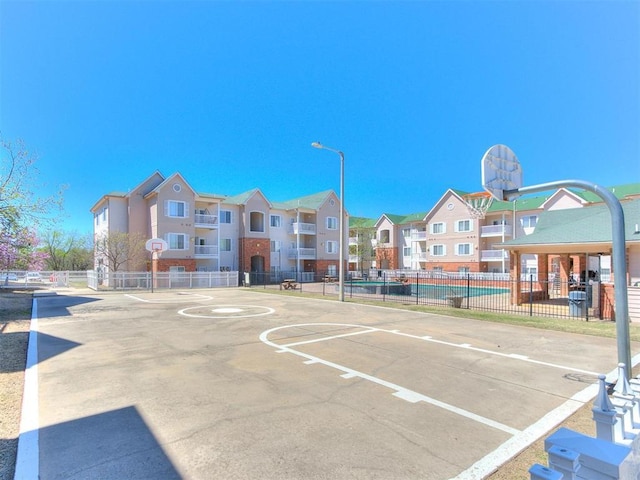 surrounding community featuring community basketball court, fence, and a residential view