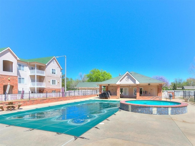 view of pool with a pool with connected hot tub, a patio, and fence