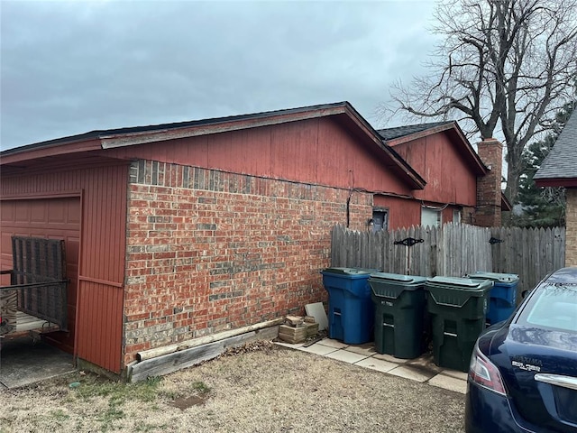 view of side of home featuring fence and brick siding