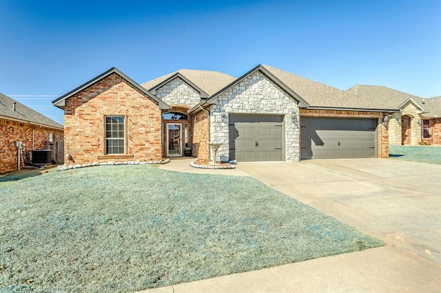 french provincial home with brick siding, central air condition unit, a shingled roof, a garage, and driveway