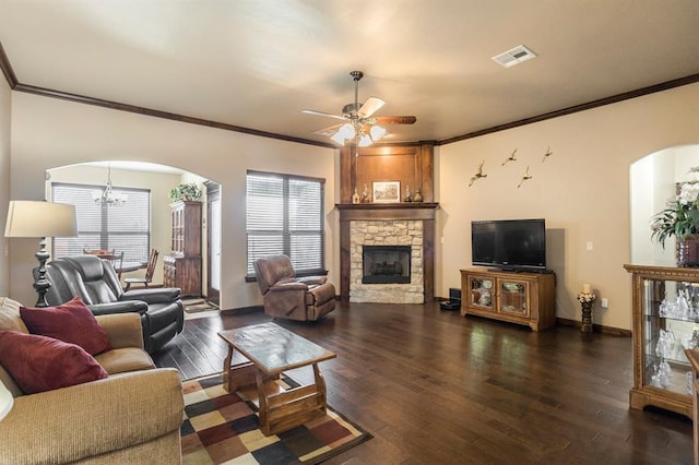 living area featuring arched walkways, visible vents, a stone fireplace, and wood finished floors